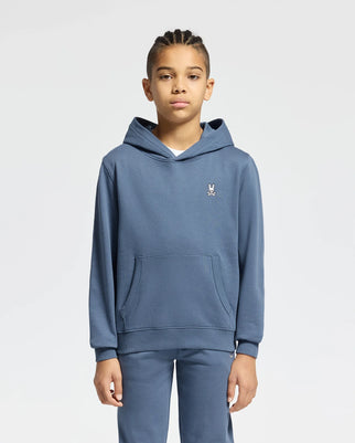 A young person models the Psycho Bunny KIDS LEVY ESSENTIAL FLEECE HOODIE - B0H859D200, made from 100% cotton French terry, set against a plain white background. The blue hooded sweatshirt and matching pants showcase a small embroidered logo on the chest and include a handy front pocket.