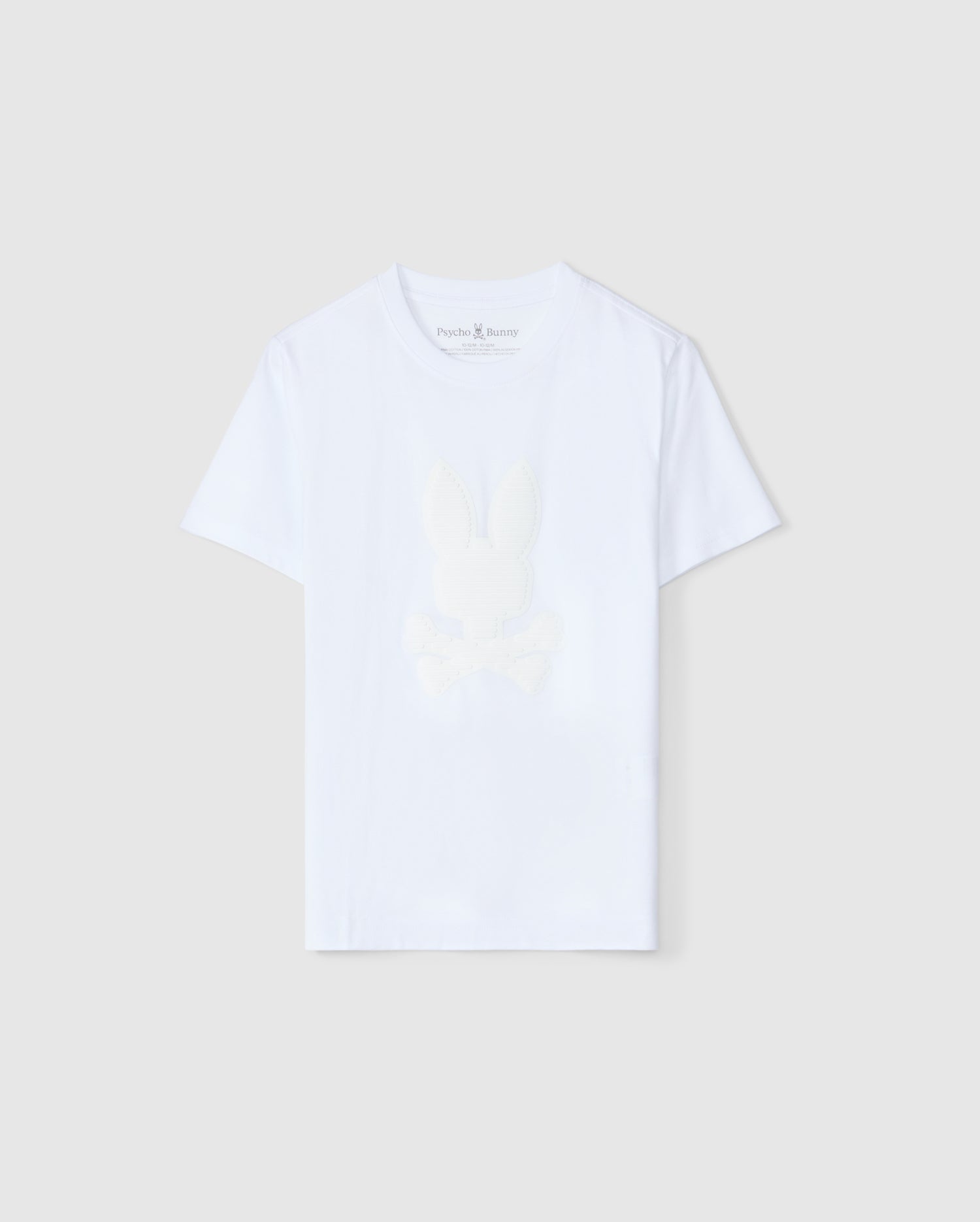 The KIDS KINGSTON GRAPHIC TEE - B0U743D200 by Psycho Bunny is a plain white T-shirt designed from a Pima cotton blend. It features a subtle center bunny graphic of a rabbit head and crossbones on the front, with a round neckline and short sleeves that complement the neutral light gray background.