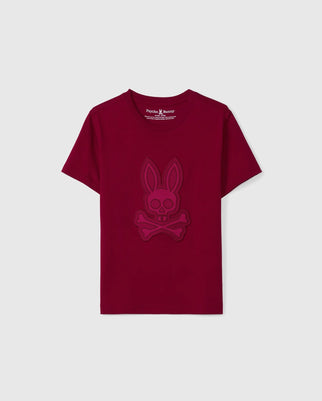 Introducing the Psycho Bunny KIDS MALTON GRAPHIC TEE - B0U795D200, a maroon kids' graphic tee featuring a subtle design of a skull and crossbones topped with bunny ears in a slightly darker shade. Made from soft Pima cotton for ultimate comfort, this stylish kids' shirt is displayed on a light grey background.