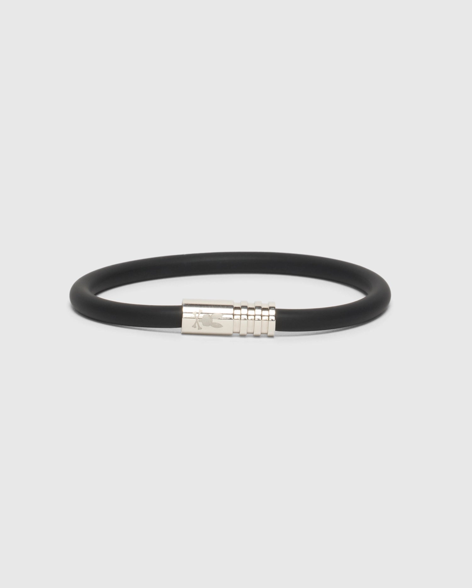 A simple yet stylish accessory, the MEN'S ROUND SILICONE BRACELET - B6A386E200 by Psycho Bunny boasts a sleek metallic clasp, elegantly presented against a plain white backdrop.