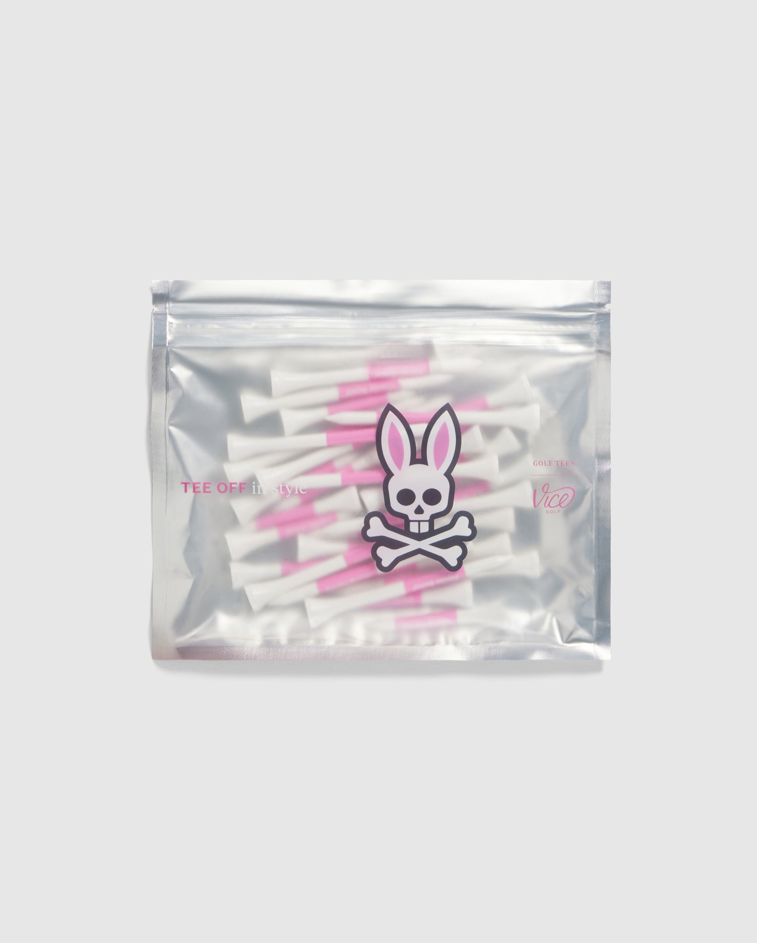 A silver plastic ziplock bag filled with quality-crafted Psycho Bunny golf tees, featuring white tees with pink stripes. The bag displays a stylized pink and white bunny skull and crossbones logo on the front. The words 