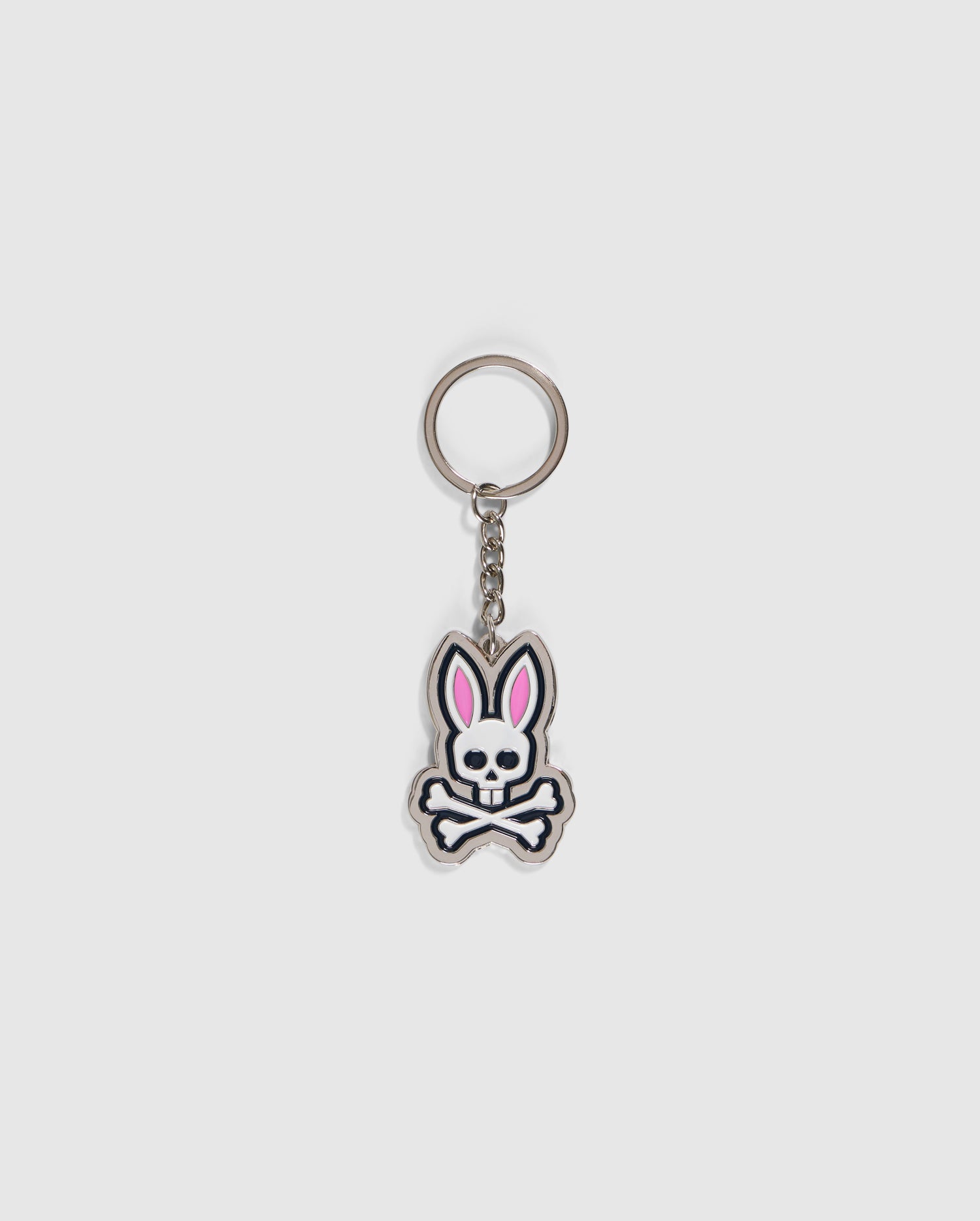 The MENS PSYCHO BUNNY KEYCHAIN - B6A708C200 from Psycho Bunny boasts a skull and crossbones design with bunny ears and pink accents. Made from durable zinc alloy, it features a metallic ring and short chain to securely hold your keys.