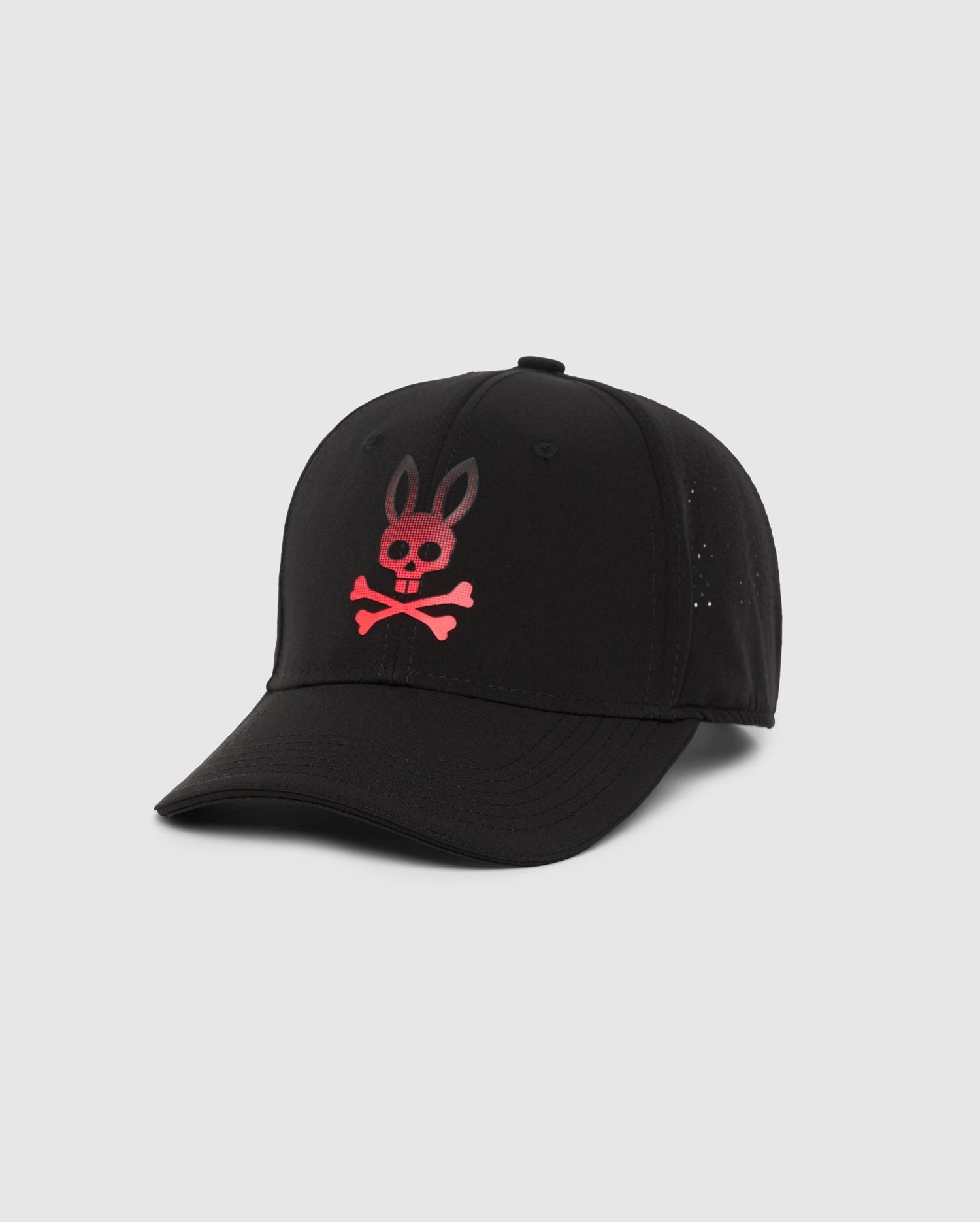 The Men's Maxwell Sport Cap in black by Psycho Bunny features a pink skull and crossbones with bunny ears design on the front. This 100% cotton cap includes a curved brim and a structured front panel, set against a white background.