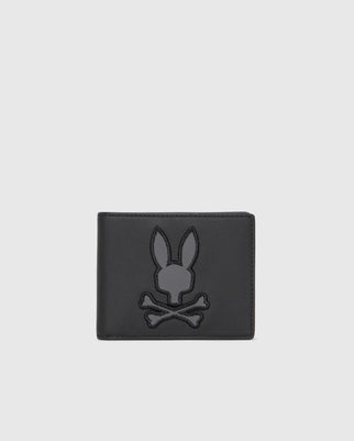 The Psycho Bunny MENS LEATHER WALLET - B6A868D200 is a luxury wallet crafted from premium leather, featuring an embossed rabbit head above crossed bones on a plain light gray background.