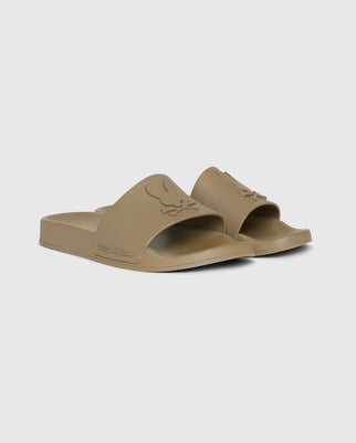 A pair of beige pool slides with an open-toe design and embossed logo on the strap. The molded footbed ensures comfort, while the slightly textured sole offers grip. The brand name "Psycho Bunny" is visible on the side of these stylish MENS LOGO SLIDES - B6A910U1FT.