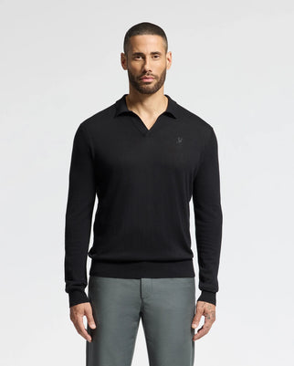 A man with short hair and a beard is wearing a Psycho Bunny MENS JOHNNY COLLAR SWEATER, product code B6E258E200, in black and gray pants, standing against a plain white background.