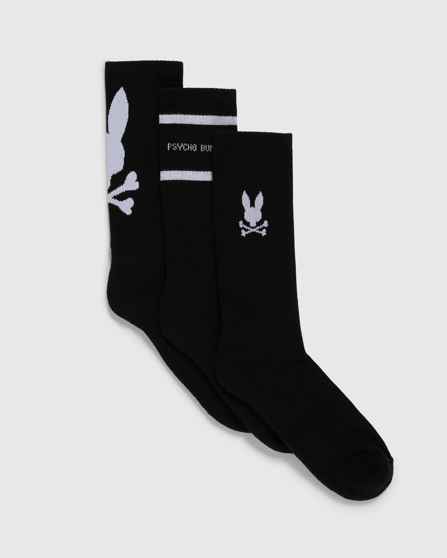 Three pairs of black sport socks with white designs are displayed. The Psycho Bunny MENS 3 PACK SPORT SOCK - B6F997D200 includes: the first pair featuring a large skull and rabbit ears graphic, the second pair with a horizontal stripe and the text 