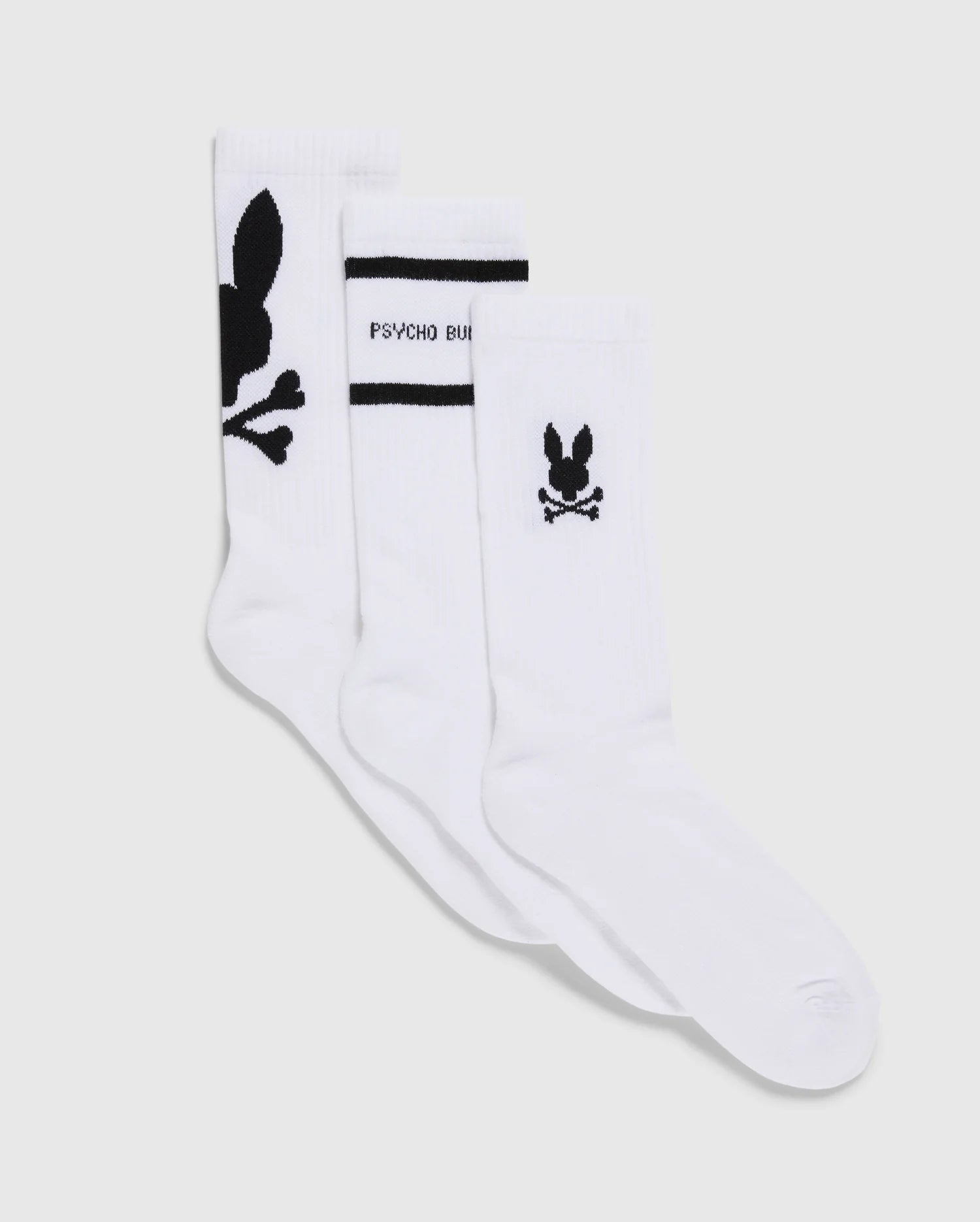 The MENS 3 PACK SPORT SOCK - B6F997D200 by Psycho Bunny features three pairs in pristine white, each made from luxurious Peruvian pima cotton. These socks are adorned with black designs: a skull with bunny ears on one pair, the phrase 