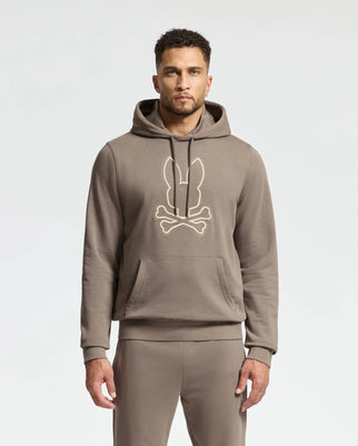 A person wearing the comfortable Psycho Bunny MENS ALEXANDER HOODIE - B6H154E200, featuring a bunny and crossbones design on the front. The outfit is completed with soft-touch matching pants, creating a perfect casual look against a plain background.