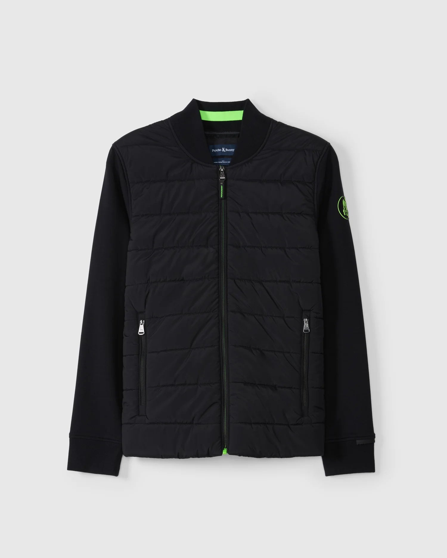 The Psycho Bunny Men's Mykel Mixed Media Jacket - B6J875D200 is a stylish black bomber jacket featuring a quilted front, ribbed collar, and green accents on the inside lining. This men's jacket comes with zippered side pockets, a green and black zip pull, and a small green logo patch on the left sleeve.