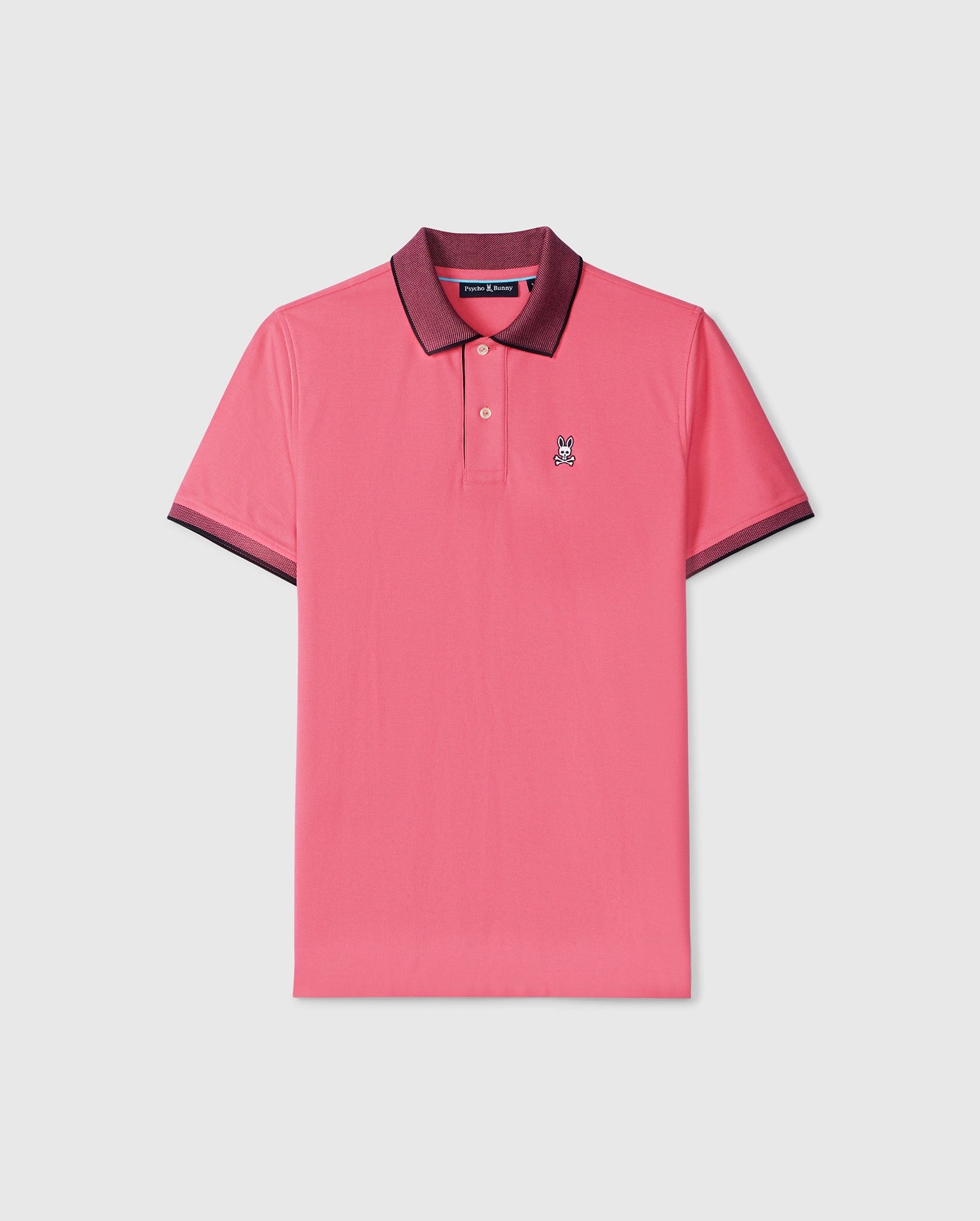 A Psycho Bunny MENS SOUTHPORT PIQUE POLO SHIRT - B6K263B200 in pink with a dark maroon collar and sleeve trim. Made from Pima cotton piqué, it features a small embroidered logo of a cartoon bunny on the left chest area. The regular fit shirt is displayed against a plain, light gray background.