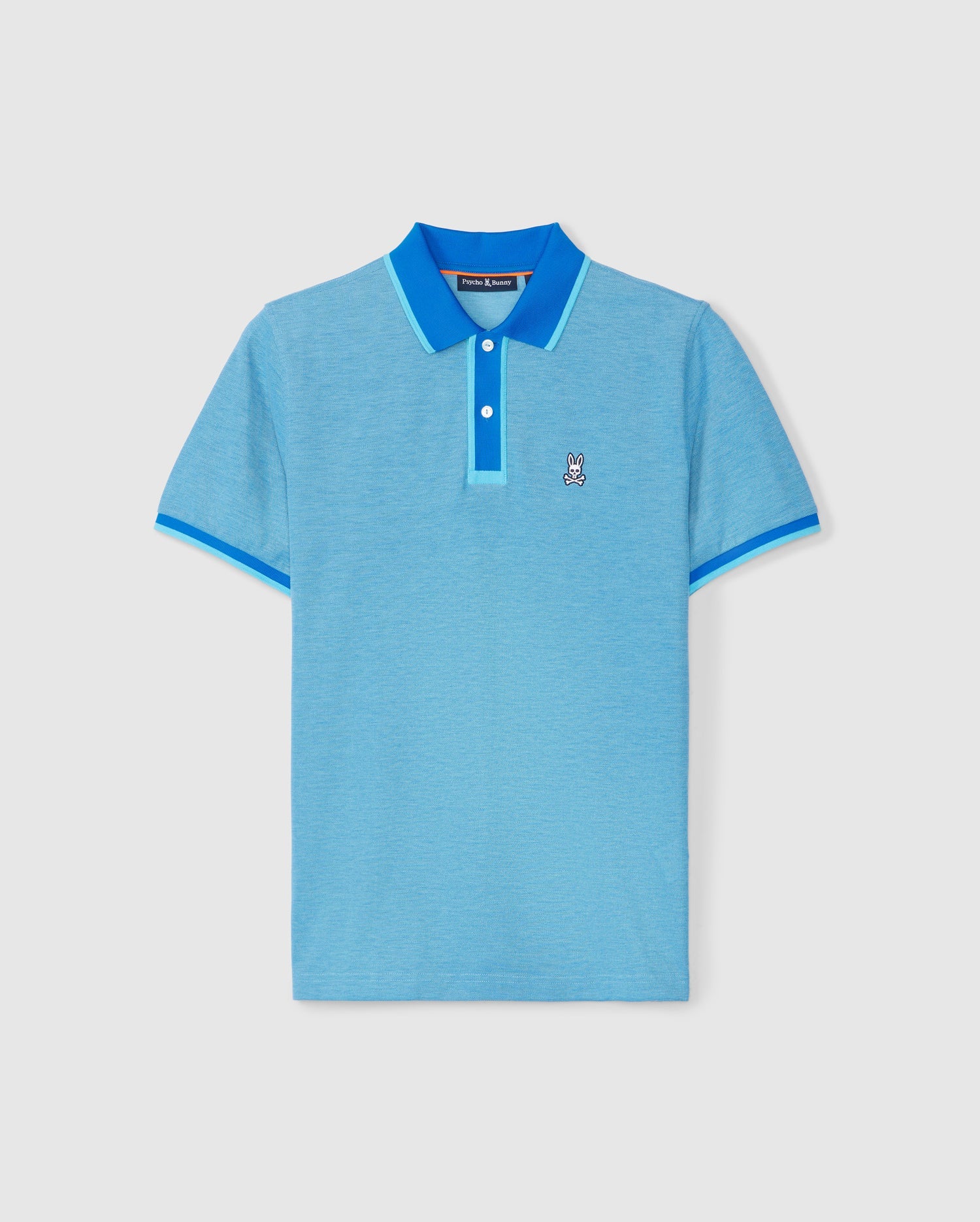 The MENS WOODWAY OXFORD POLO - B6K405C200 by Psycho Bunny is crafted from premium Pima cotton in light blue, featuring a royal blue collar and sleeve trim. It includes a classic two-button placket and showcases an embroidered white and black rabbit logo on the left chest.