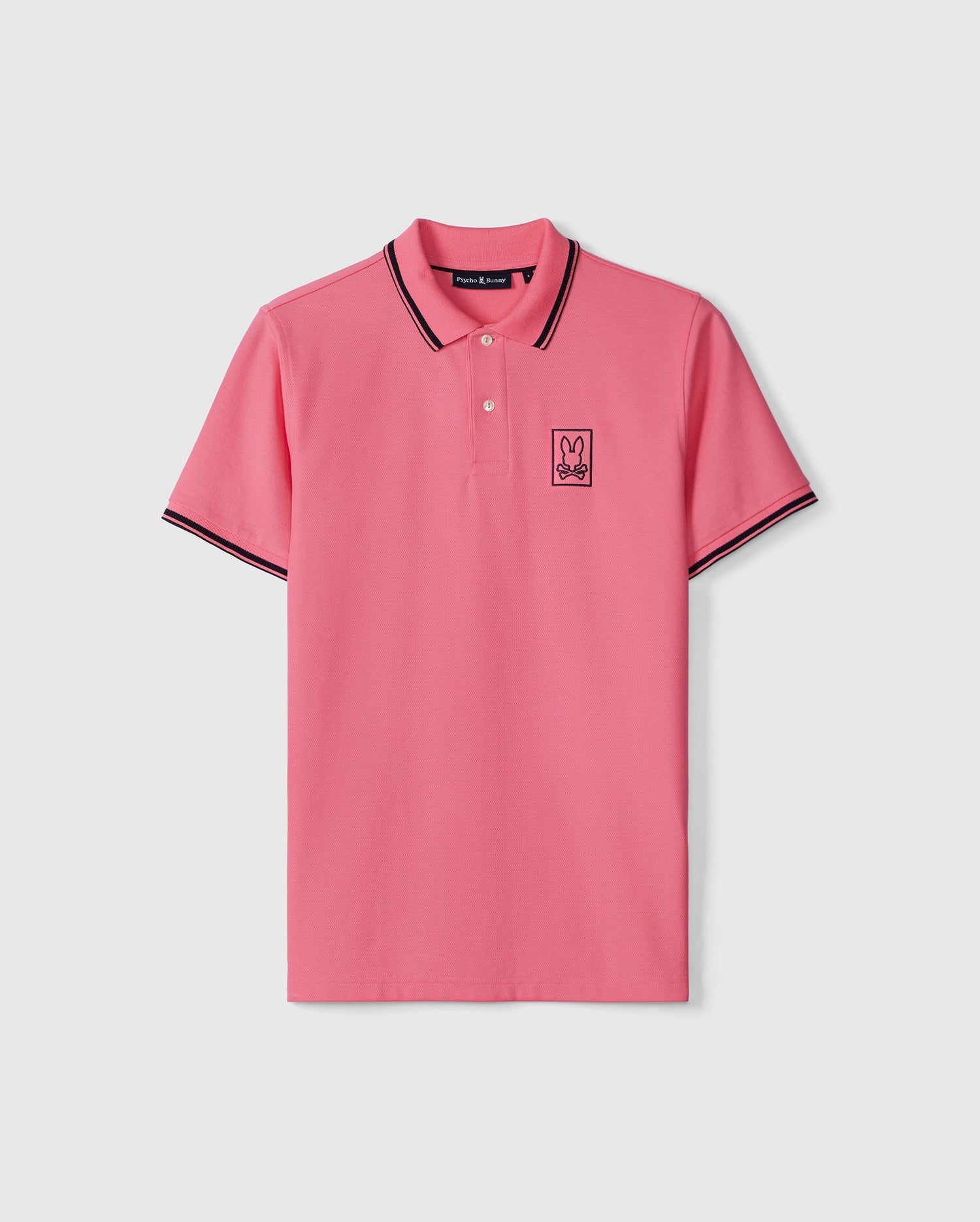 A pink Psycho Bunny polo shirt with black and white striped detailing on the collar and sleeves, featuring a small embroidered rabbit logo on the left chest. The shirt is displayed on a plain background.