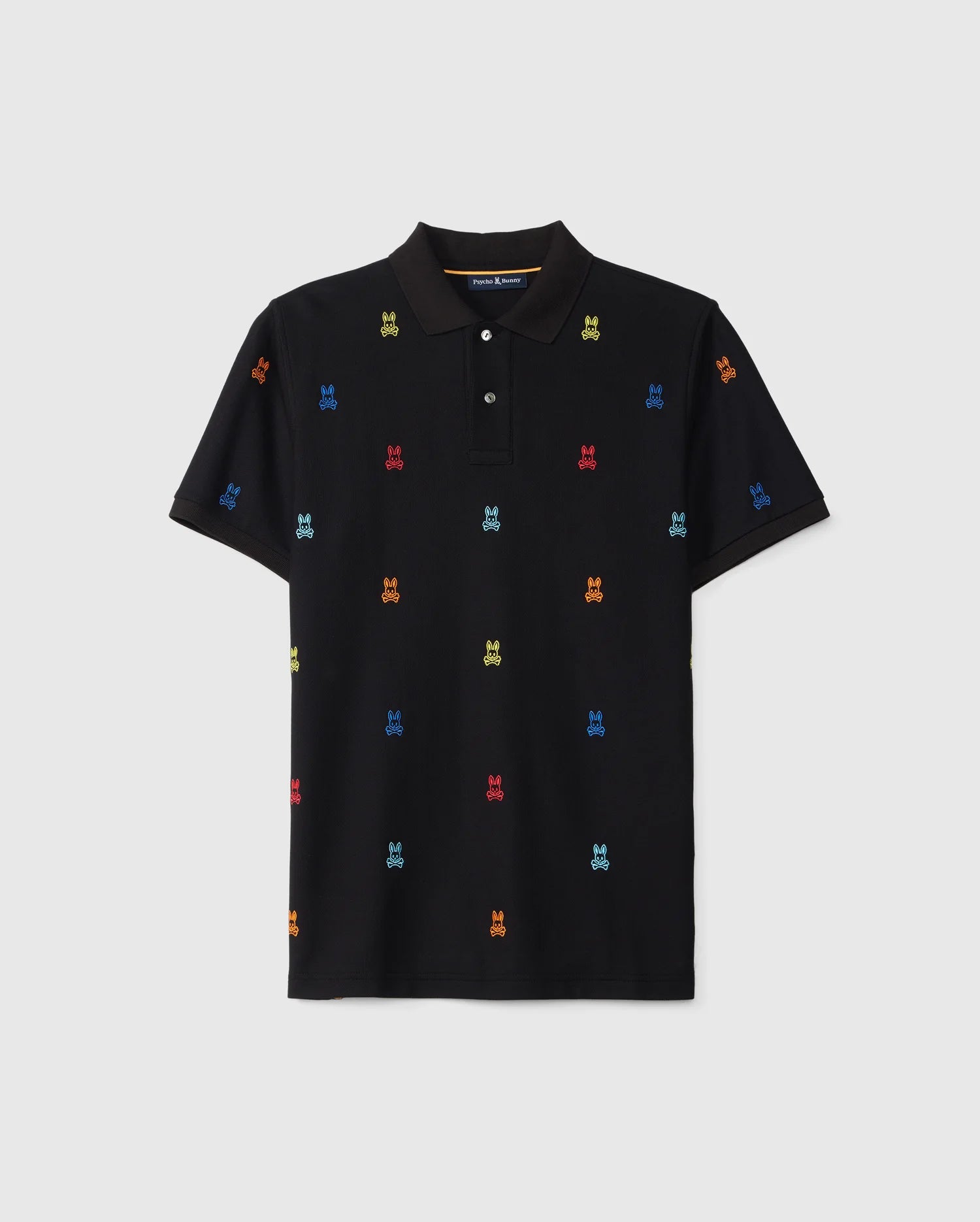 A black Psycho Bunny MENS BONHAM PIQUE POLO - B6K501C200 featuring a pattern of small, colorful embroidered motifs. The shirt has a classic collar, three-button placket, and short sleeves. The motifs in this jacquard pattern include bright colors like red, green, blue, and yellow spread evenly across the fabric.