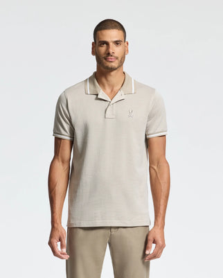 A man in a Psycho Bunny MENS WARSAW JACQUARD PIQUE POLO (B6K901E200), light gray with white trim and an embroidered logo, stands against a plain white background. The jacquard-knit fabric enhances his appearance, complementing his short hair and beard.