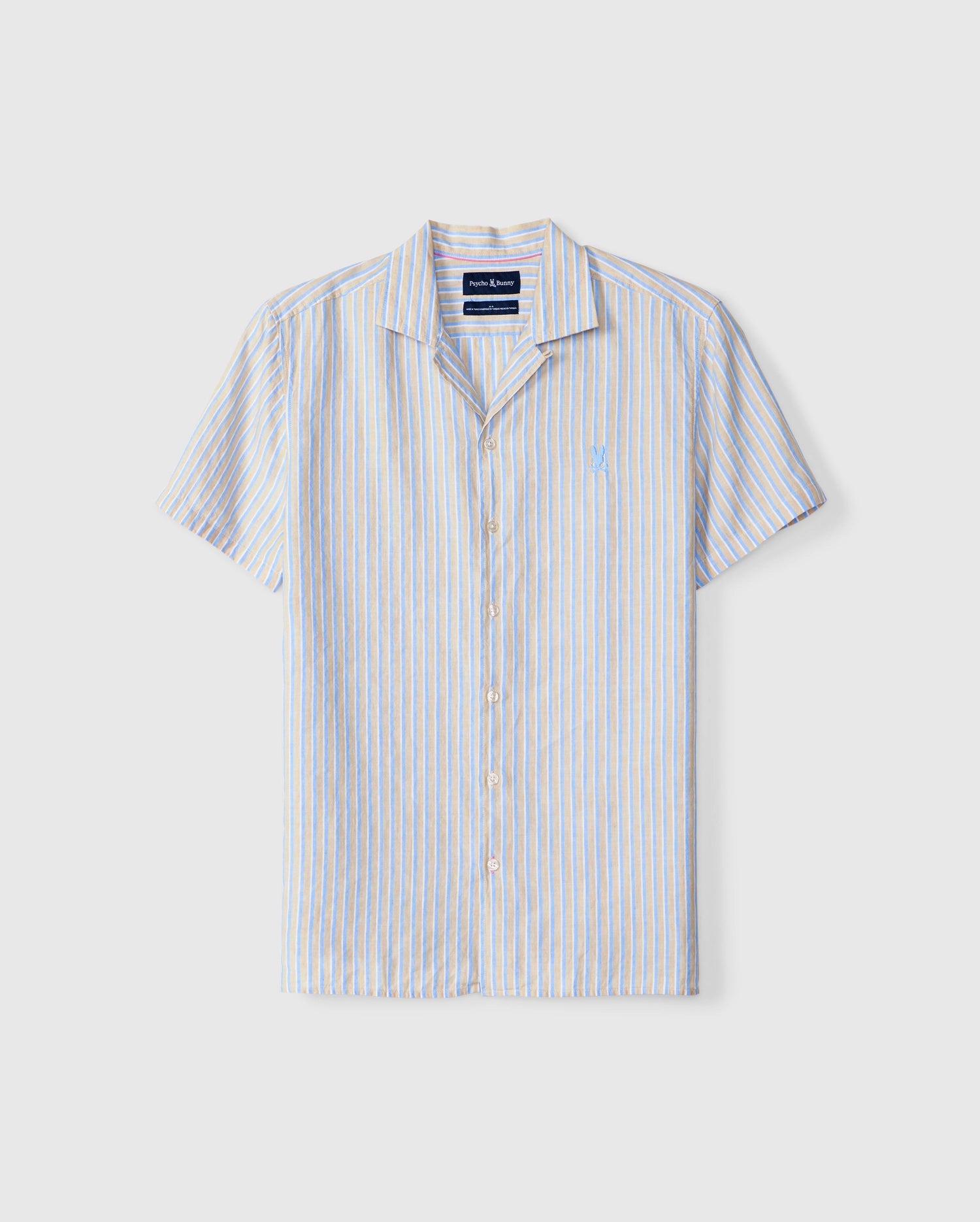 A vertical image of the Psycho Bunny MENS JUSTIN LINEN CAMP SHIRT - B6Q585C200, a vertically striped, button-up linen shirt with short sleeves, featuring shades of blue, white, and pale yellow. The shirt is neatly displayed on a plain background.