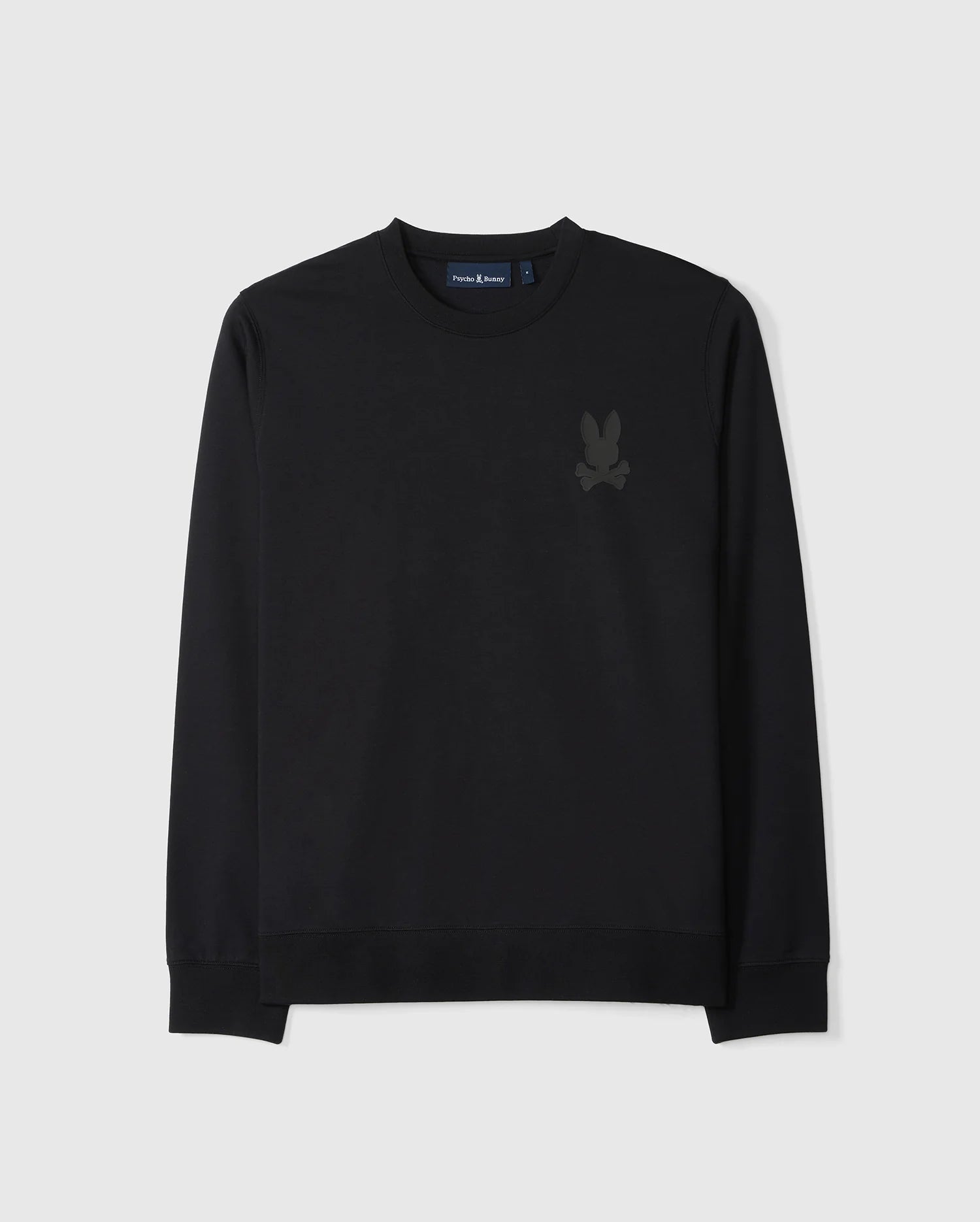 The Psycho Bunny MENS HOUSTON FRENCH TERRY CREWNECK - B6S462C200 is a black crewneck sweatshirt with long sleeves, crafted from premium Micro French Terry cotton for the ultimate comfort. It features ribbed cuffs and a ribbed waistband, and is adorned with a subtle, small dark graphic of a rabbit head and crossbones on the left chest area.