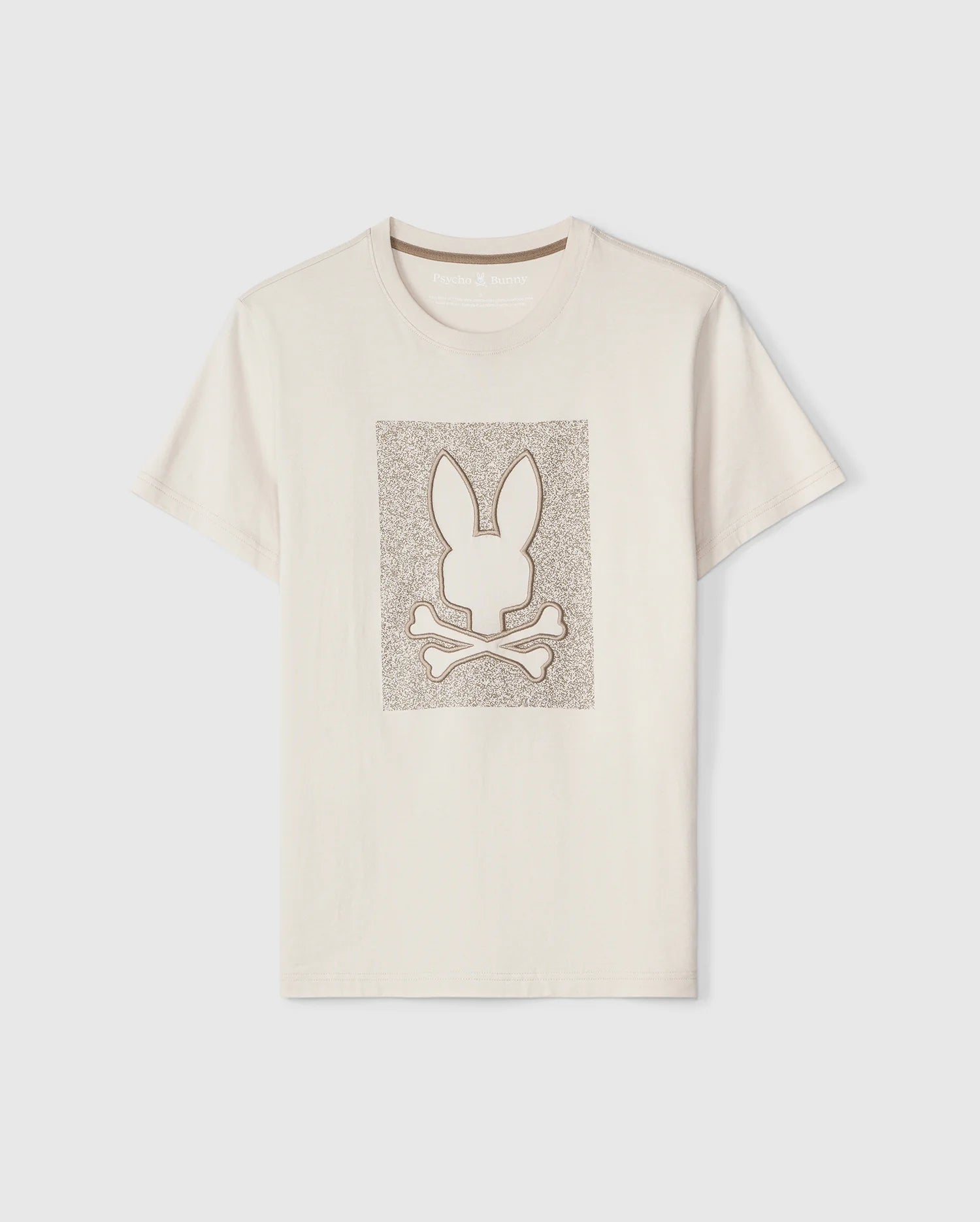 This beige Psycho Bunny MENS LIVINGSTON GRAPHIC TEE - B6U247B2TS, made from ultra-soft Peruvian Pima cotton, features a bold rectangular graphic in the center with an outline of a bunny head and crossbones beneath it, creating a playful take on the classic skull and crossbones design. The textured pattern adds depth to this unique bunny design.