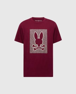 The Psycho Bunny MENS ROCKTON GRAPHIC TEE (B6U247C200) in burgundy features a bunny silhouette above crossed bones on a textured rectangular background and is crafted from Pima cotton in Peru.