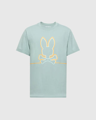 The Psycho Bunny Mens Dacano Front Graphic Tee (B6U314E200) is a light green, performance-focused shirt with a stylized bunny head and crossed bones in pale yellow and white. It features short sleeves, a round neckline, and offers comfort with its regular fit.