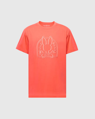 The bright coral MENS MELBOURNE GRAPHIC TEE (B6U410F200) by Psycho Bunny, made from eco-friendly Pima Cotton, showcases a front logo featuring a stylized rabbit head above crossbones with "Psycho Bunny" in the design, set against a light gray background.