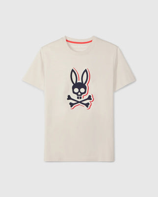 The Psycho Bunny Men's Kayden Graphic Tee (B6U676C200) in beige, made of soft Pima cotton, features a striking black and white skull with bunny ears above crossed bones outlined in red on the front, along with an embroidered logo for extra flair.