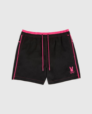 Introducing the Psycho Bunny MENS ROCKDALE LIGHTWEIGHT SWIM TRUNK - B6W653C200, a pair of black beach shorts featuring neon pink accents. These lightweight bathing suits have pink piping along the sides, a pink drawstring at the waistband, and a pink rabbit head with crossbones logo on the left leg. The background is plain and white.