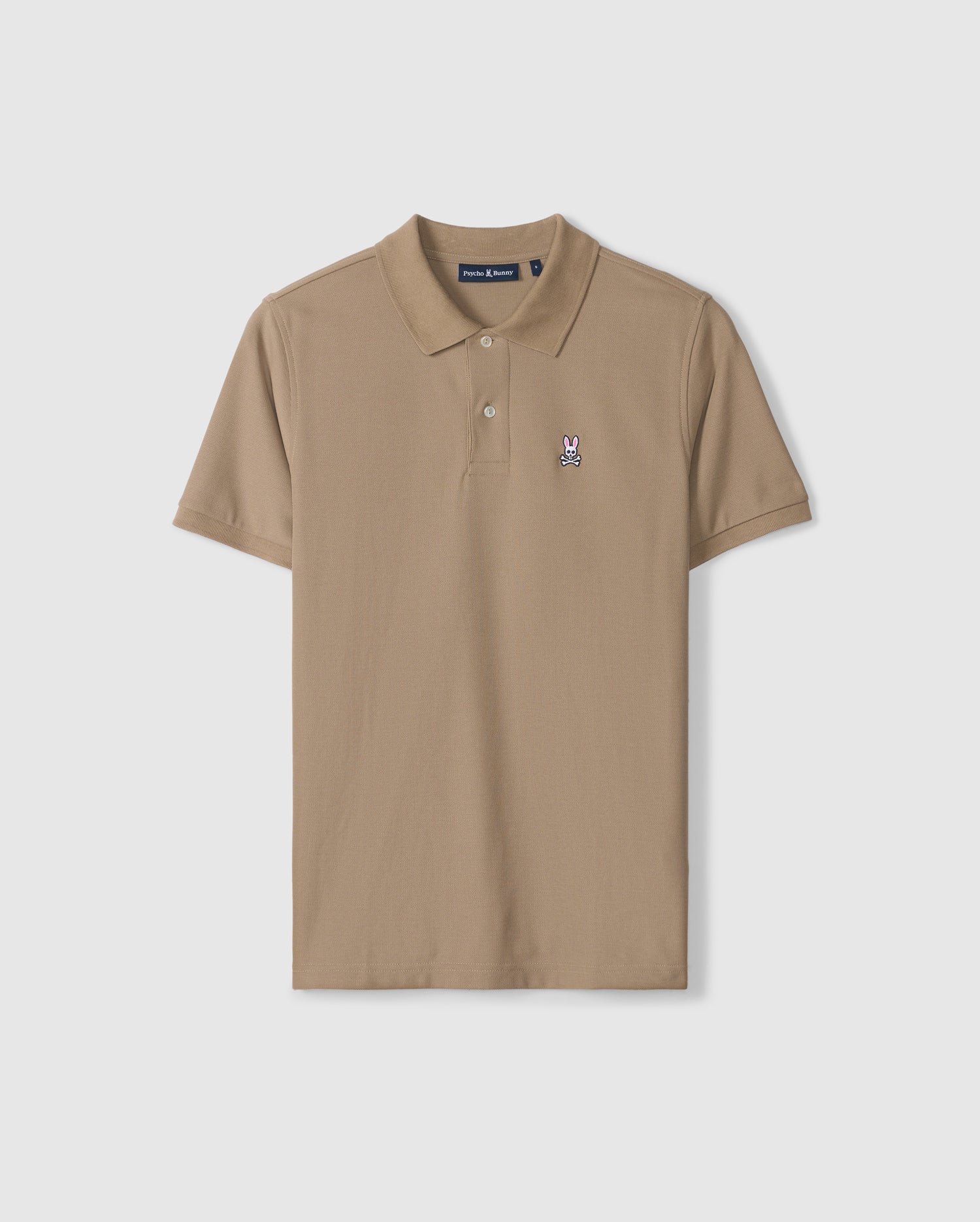 The BIG AND TALL CLASSIC PIQUE POLO SHIRT - B9K001CRPC by Psycho Bunny is a tan, short-sleeve polo featuring a small embroidered rabbit and crossed bones logo on the left chest. Crafted from soft Peruvian cotton, this shirt boasts a classic collar and a two-button placket.