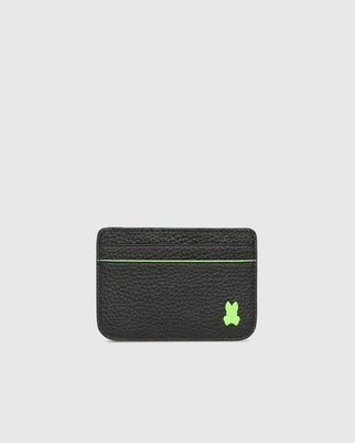 The Psycho Bunny CARD CASE - B6A409B200 is a black textured leather cardholder featuring a neon green bunny patch in the bottom right corner. A green stitched line near the top indicates a card slot, set against a plain light gray background.